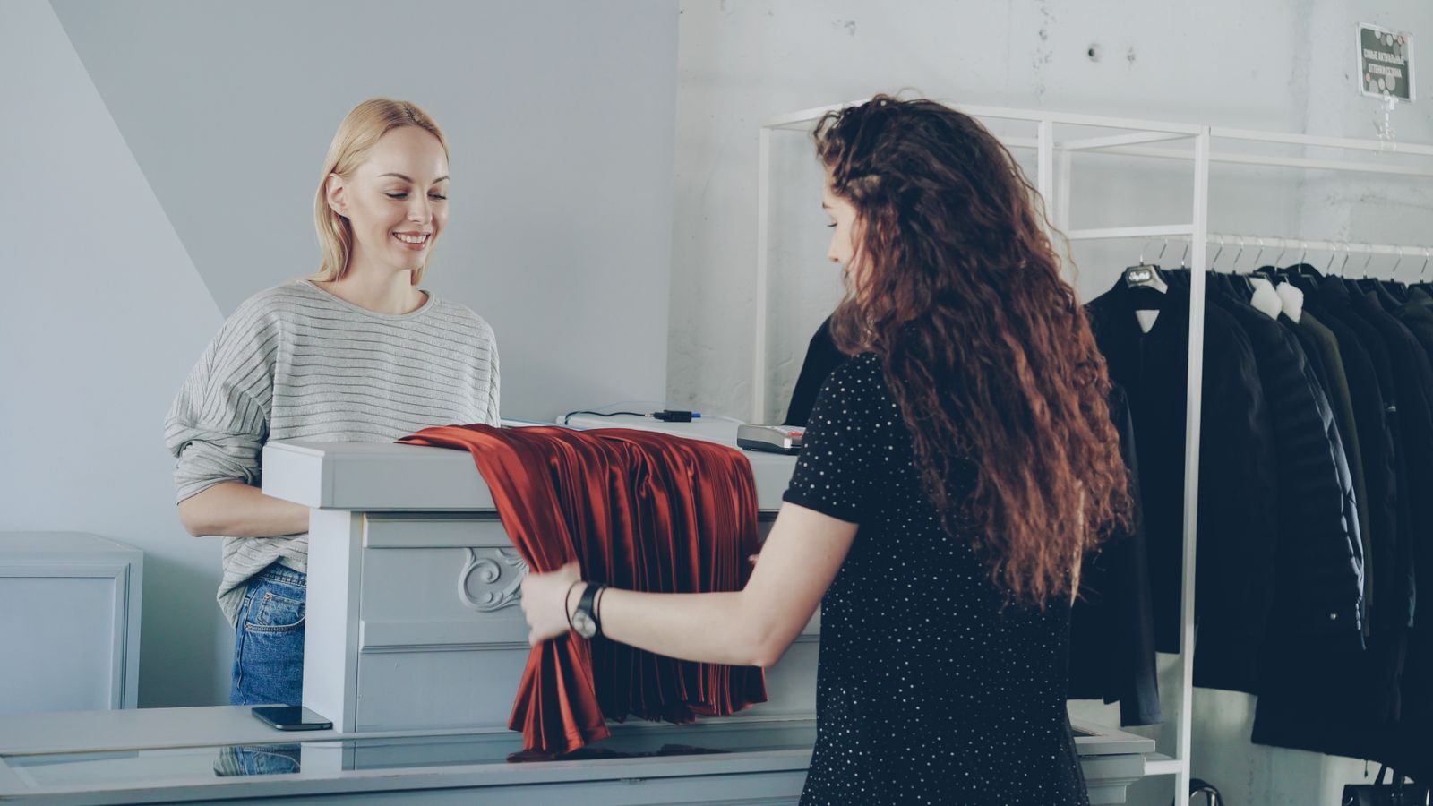 A smiling shop assistant helping a customer at a boutique counter